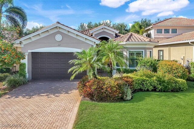 3267 Pacific Dr, Naples, FL 34119 - mediterranean / spanish home featuring an attached garage, decorative driveway, a front lawn, stucco siding, and a tiled roof