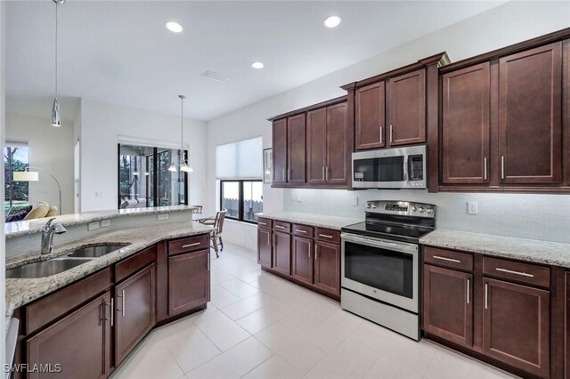 3267 Pacific Dr, Naples, FL 34119 - kitchen with stainless steel appliances, a sink, light stone countertops, pendant lighting, and dark brown cabinetry