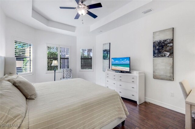 3267 Pacific Dr, Naples, FL 34119 - bedroom with dark wood-style flooring, baseboards, a tray ceiling, and ceiling fan
