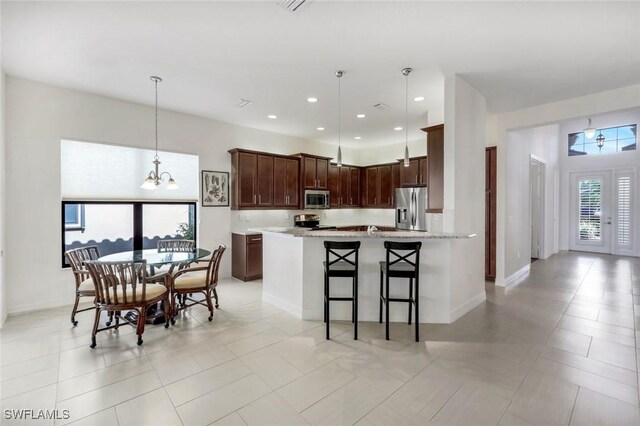 3267 Pacific Dr, Naples, FL 34119 - kitchen featuring stainless steel appliances, decorative light fixtures, a kitchen bar, recessed lighting, and dark brown cabinetry