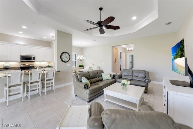 living room with light tile patterned flooring, visible vents, recessed lighting, ceiling fan with notable chandelier, and a raised ceiling