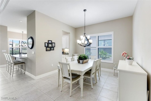 dining room with baseboards, a notable chandelier, and light tile patterned flooring