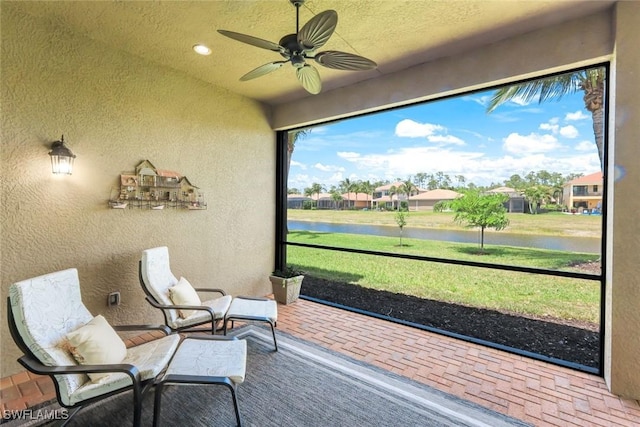 sunroom / solarium with a ceiling fan and a water view