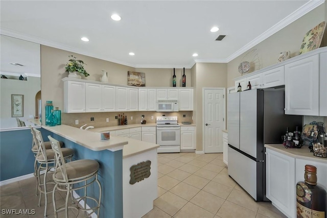 12732 Fox Ridge Dr, Bonita Springs, FL 34135 - kitchen with visible vents, white cabinets, white appliances, a kitchen bar, and a peninsula