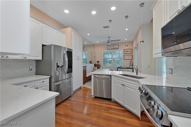15890 Delasol Ln, Naples, FL 34110 - kitchen with appliances with stainless steel finishes, light wood finished floors, white cabinets, and recessed lighting