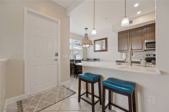18276 Creekside Preserve Loop Unit 102, Fort Myers, FL 33908 - kitchen with appliances with stainless steel finishes, tasteful backsplash, light tile patterned floors, a peninsula, and light countertops