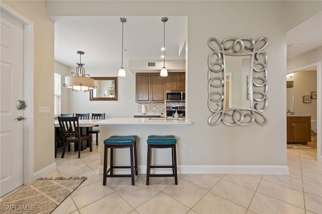 18276 Creekside Preserve Loop Unit 102, Fort Myers, FL 33908 - kitchen featuring stainless steel microwave, decorative backsplash, light countertops, and light tile patterned flooring