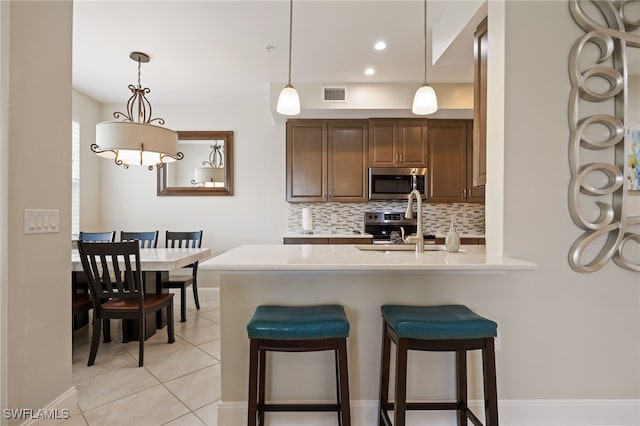 18276 Creekside Preserve Loop Unit 102, Fort Myers, FL 33908 - kitchen featuring stainless steel appliances, backsplash, light countertops, a breakfast bar, and light tile patterned floors