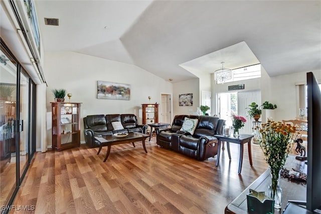 1803 Golfside Village Dr, Lehigh Acres, FL 33936 - living room featuring a chandelier, vaulted ceiling, and light wood-style flooring