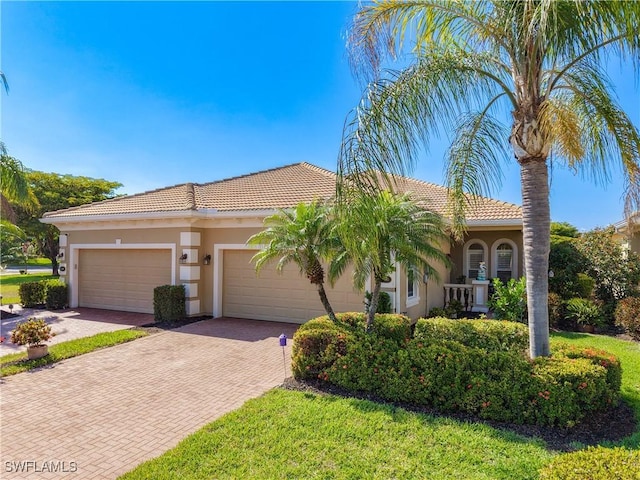 13885 Cleto Dr, Estero, FL 33928 - view of front facade featuring an attached garage, a tiled roof, stucco siding, and decorative driveway