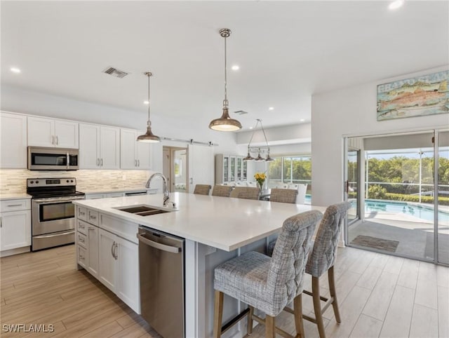 14701 Eden St, Fort Myers, FL 33908 - kitchen featuring a sink, stainless steel appliances, backsplash, white cabinetry, and visible vents