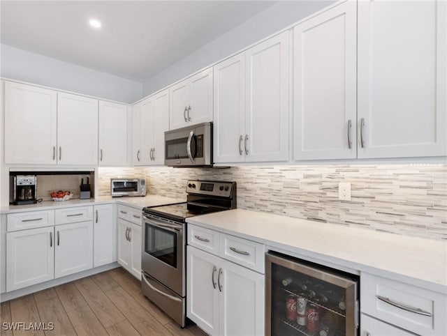 14701 Eden St, Fort Myers, FL 33908 - kitchen featuring beverage cooler, light wood finished floors, light countertops, white cabinets, and appliances with stainless steel finishes