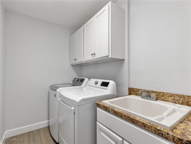 14701 Eden St, Fort Myers, FL 33908 - laundry room featuring washer and clothes dryer, a sink, light wood-type flooring, cabinet space, and baseboards