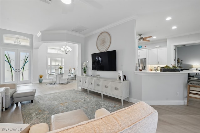 living room featuring crown molding, recessed lighting, light wood finished floors, and ceiling fan with notable chandelier