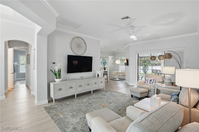living area with arched walkways, baseboards, plenty of natural light, and light wood-type flooring