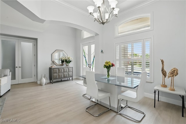 dining space with french doors, crown molding, arched walkways, wood finished floors, and a notable chandelier