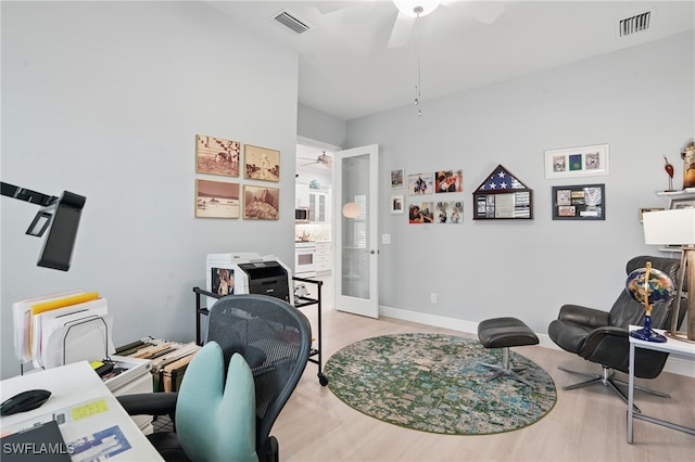 office with light wood-style floors, a ceiling fan, french doors, and visible vents