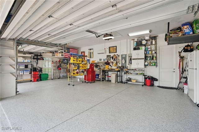 garage featuring a workshop area, a garage door opener, and freestanding refrigerator