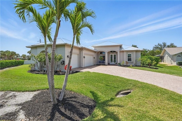 view of front of property with a front yard, decorative driveway, stucco siding, french doors, and an attached garage
