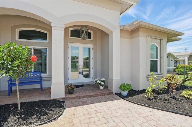 view of exterior entry featuring french doors and stucco siding