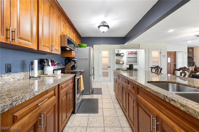 kitchen featuring stainless steel appliances, stone countertops, brown cabinetry, and light tile patterned flooring