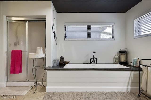 full bath featuring a shower stall, a wealth of natural light, and a bathing tub