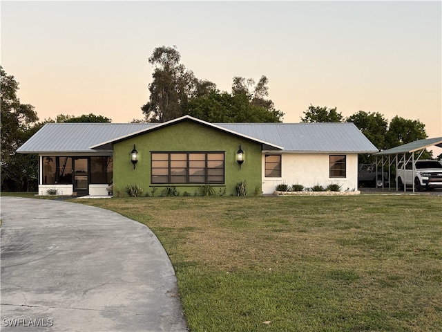 ranch-style home featuring a sunroom, metal roof, a front yard, and stucco siding