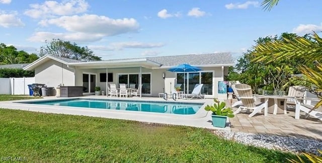 back of house featuring a patio, stucco siding, an outdoor pool, fence, and a lawn