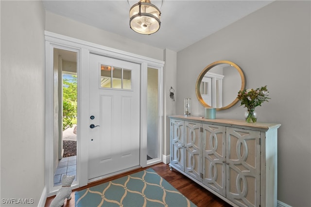 foyer entrance with dark wood-type flooring and baseboards