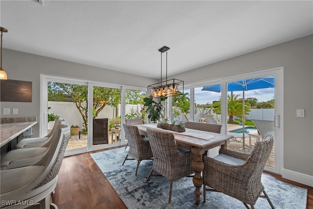 dining area with an inviting chandelier, baseboards, and dark wood finished floors
