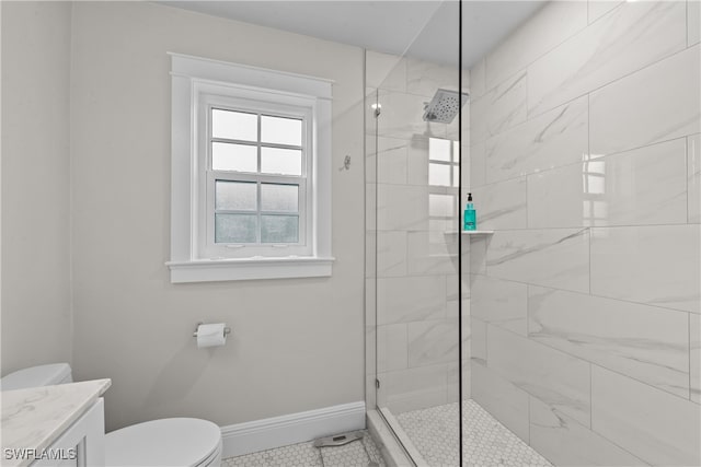bathroom featuring vanity, baseboards, tile patterned floors, toilet, and tiled shower