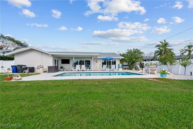 rear view of property featuring a patio, a yard, fence, and stucco siding