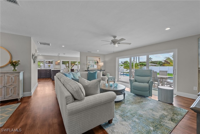 living room featuring dark wood-type flooring, a ceiling fan, visible vents, recessed lighting, and baseboards