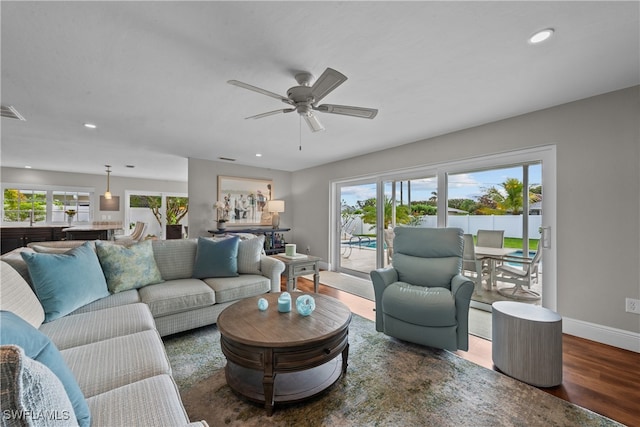 living area featuring baseboards, plenty of natural light, ceiling fan, and wood finished floors