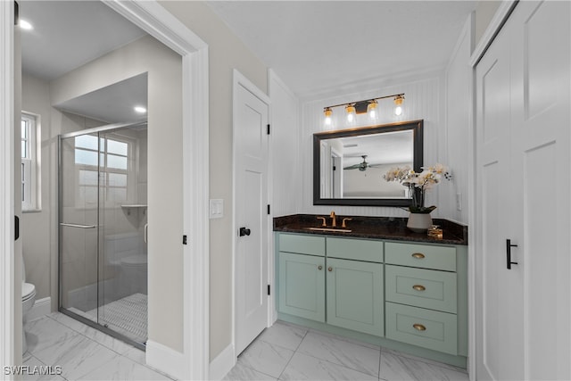 bathroom with ceiling fan, vanity, toilet, marble finish floor, and a stall shower
