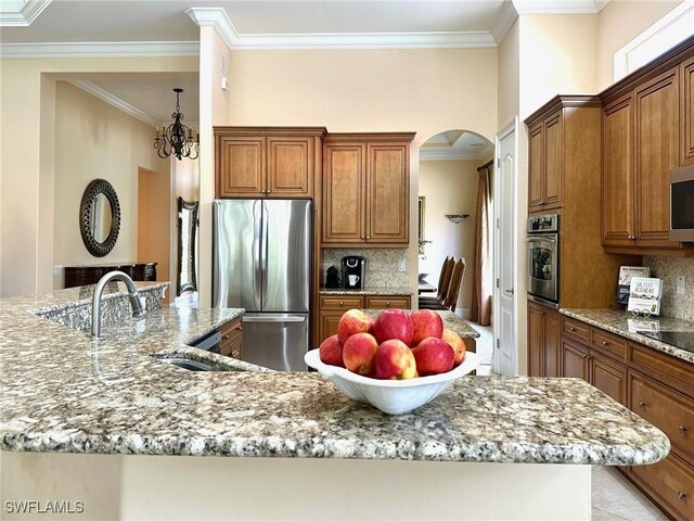 12125 Via Cercina Dr, Bonita Springs, FL 34135 - kitchen featuring arched walkways, ornamental molding, light stone counters, and stainless steel appliances