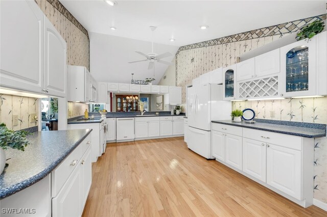 3098 Greenflower Ct, Bonita Springs, FL 34134 - kitchen with dark countertops, white appliances, glass insert cabinets, light wood-type flooring, and wallpapered walls
