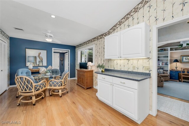 3098 Greenflower Ct, Bonita Springs, FL 34134 - kitchen featuring a ceiling fan, dark countertops, light wood-type flooring, white cabinets, and wallpapered walls