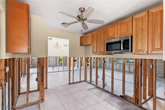 6181 Plumosa Ave, Fort Myers, FL 33908 - kitchen with brown cabinetry, ceiling fan with notable chandelier, stainless steel microwave, and plenty of natural light