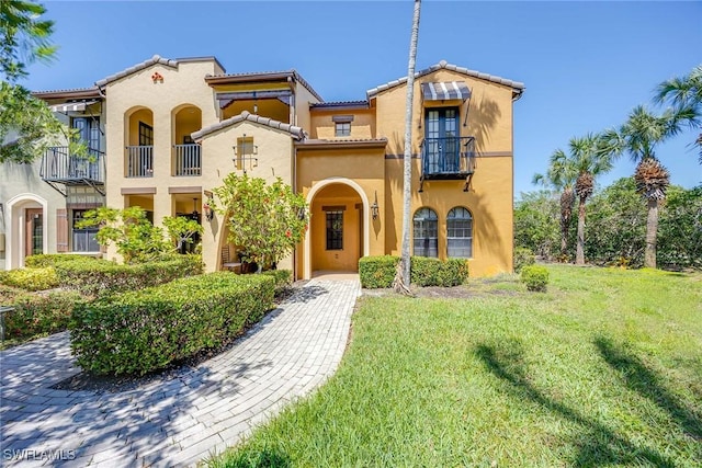 9134 Chula Vista St Unit 125, Naples, FL 34113 - mediterranean / spanish house featuring a tile roof, a balcony, a front lawn, and stucco siding