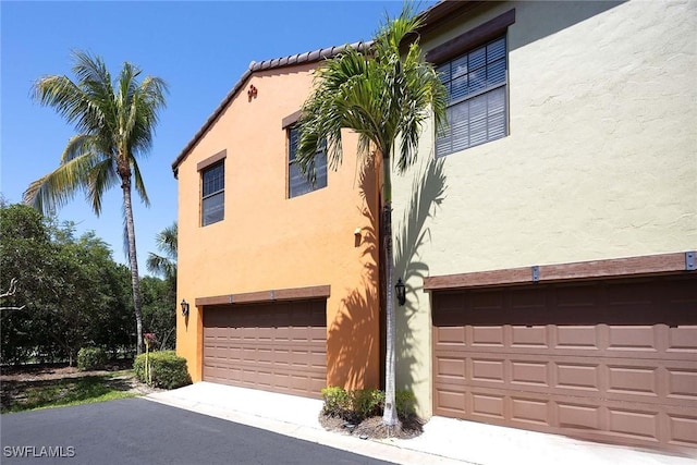 9134 Chula Vista St Unit 125, Naples, FL 34113 - view of side of home with a garage, aphalt driveway, and stucco siding