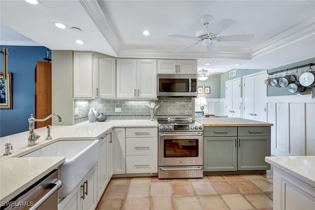 3100 Gulf Shore Blvd N Unit 103, Naples, FL 34103 - kitchen with stainless steel appliances, a tray ceiling, backsplash, a ceiling fan, and ornamental molding