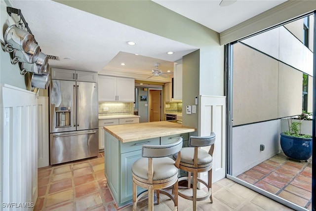 3100 Gulf Shore Blvd N Unit 103, Naples, FL 34103 - kitchen with high end refrigerator, wood counters, decorative backsplash, a kitchen bar, and ceiling fan