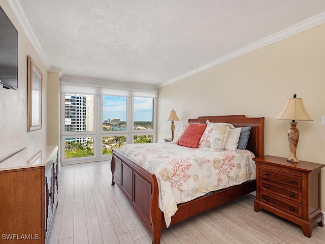 bedroom featuring ornamental molding and light wood finished floors