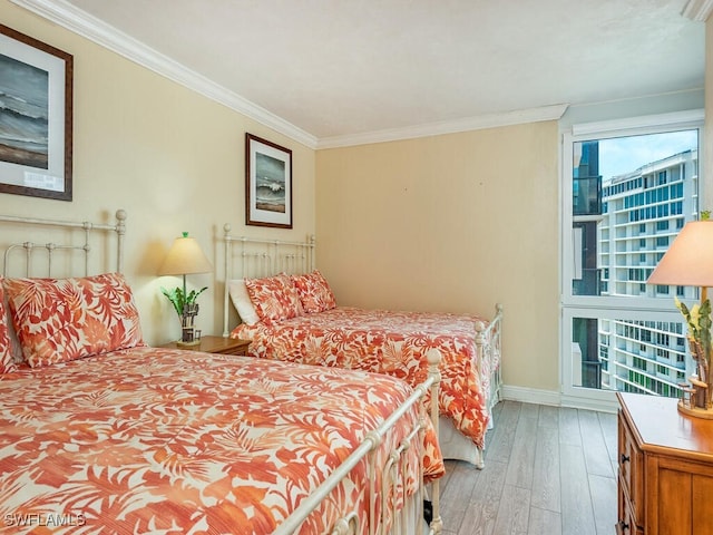 bedroom with crown molding, baseboards, wood finished floors, and multiple windows