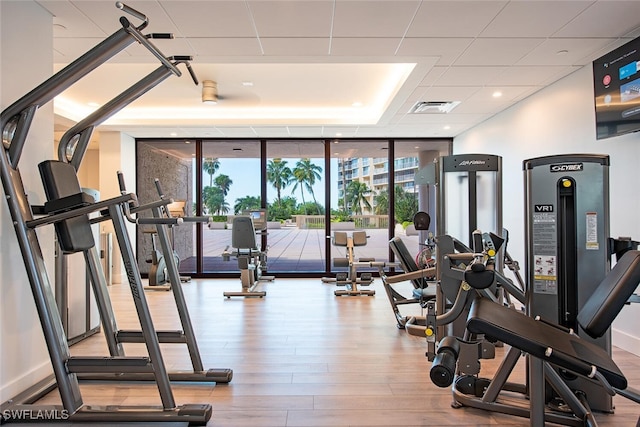 gym featuring wood finished floors, expansive windows, and visible vents