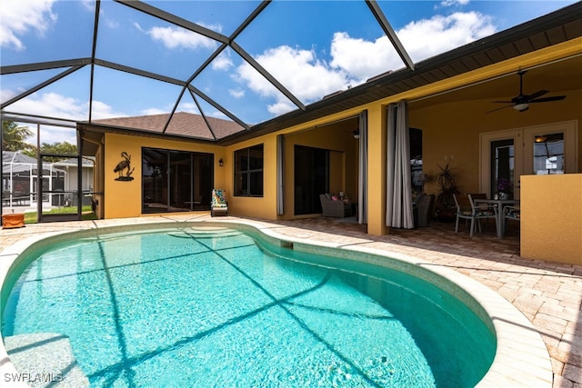 pool with a patio, glass enclosure, and a ceiling fan