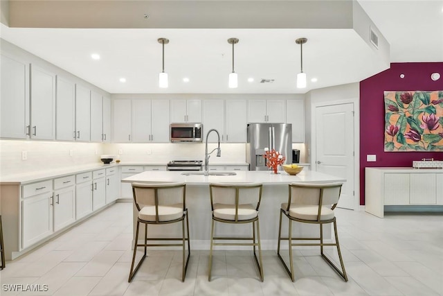 190 Indies Dr E Unit 102, Naples, FL 34114 - kitchen with tasteful backsplash, light countertops, a breakfast bar, an island with sink, and stainless steel appliances