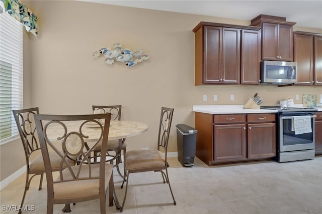 kitchen featuring light tile patterned floors, light countertops, baseboards, and appliances with stainless steel finishes