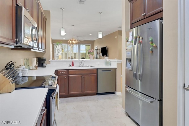 kitchen featuring a sink, a chandelier, pendant lighting, light countertops, and appliances with stainless steel finishes